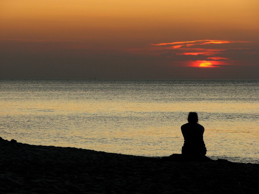 person sitting alone at sunset